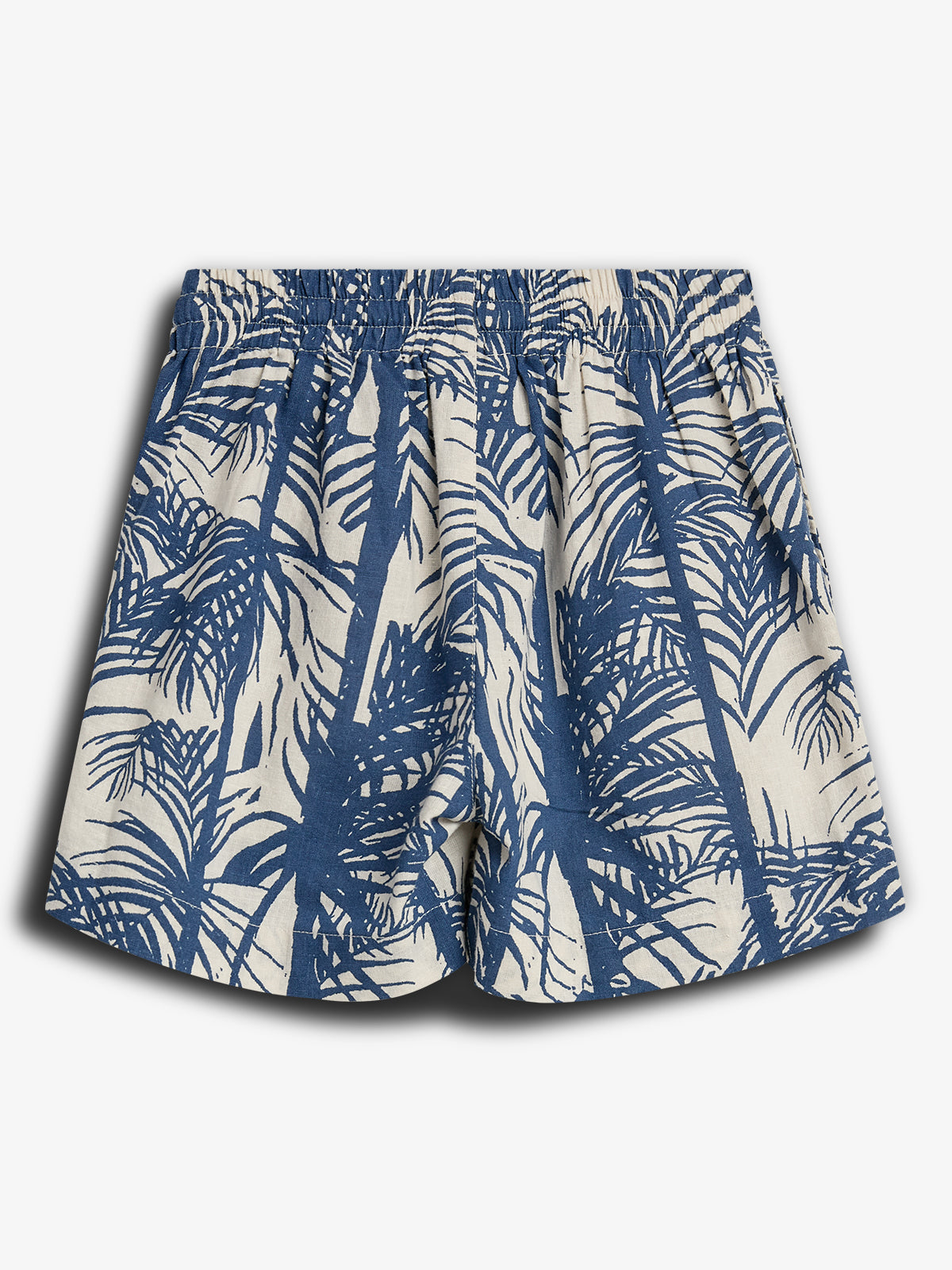 Katoenen shorts met elastische tailleband, hebben een blauw-witte palmboomprint. De achtergrond is effen wit, wat de zomerse stijl benadrukt in een casual setting.