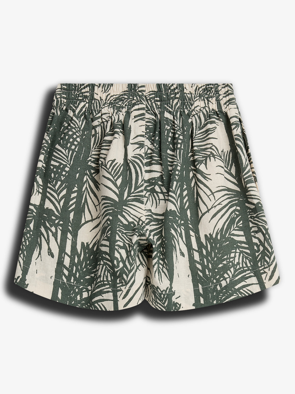 Een korte broek met een elastische tailleband, bedrukt met een groen palmboompatroon op een crèmekleurige achtergrond. De broek ligt plat tegen een witte achtergrond.