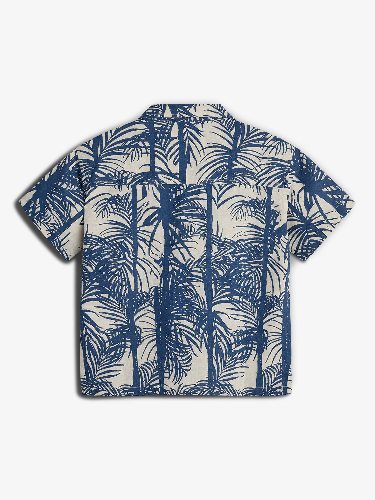 Een beige shirt met korte mouwen bedrukt met blauwe palmboompatronen, verspreid over de gehele stof. De achtergrond is effen wit zonder verdere elementen.