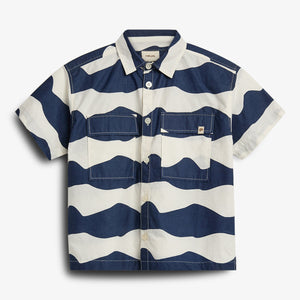 Een overhemd met brede horizontale blauwe en witte strepen, knopen aan de voorkant en twee borstzakken, ligt op een witte achtergrond. Bovenaan in de kraag staat "POLO RALPH LAUREN".