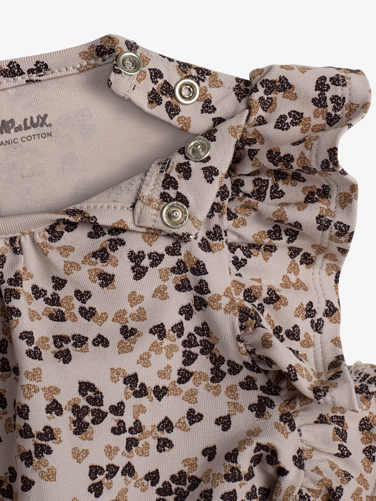 Shirt met drukknoopjes en rouches, bedrukt met kleine zwart-bruine bladeren op een crèmekleurige achtergrond. Tekst: "POMPdeLUX ORGANIC COTTON".