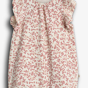 Rompertje - Het rompertje heeft een vrolijk bloemetjespatroon in rood en beige. De ruches accentueren de schouders, in een neutrale achtergrond. Tekst: "POMP.LUX ORGANIC COTTON".