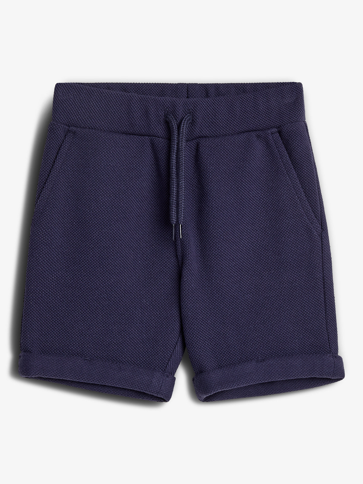 Donkerblauwe korte broek met opgerolde zoom en koordsluiting, gemaakt van gestructureerde stof. De broek heeft twee zijzakken en ligt op een witte achtergrond.
