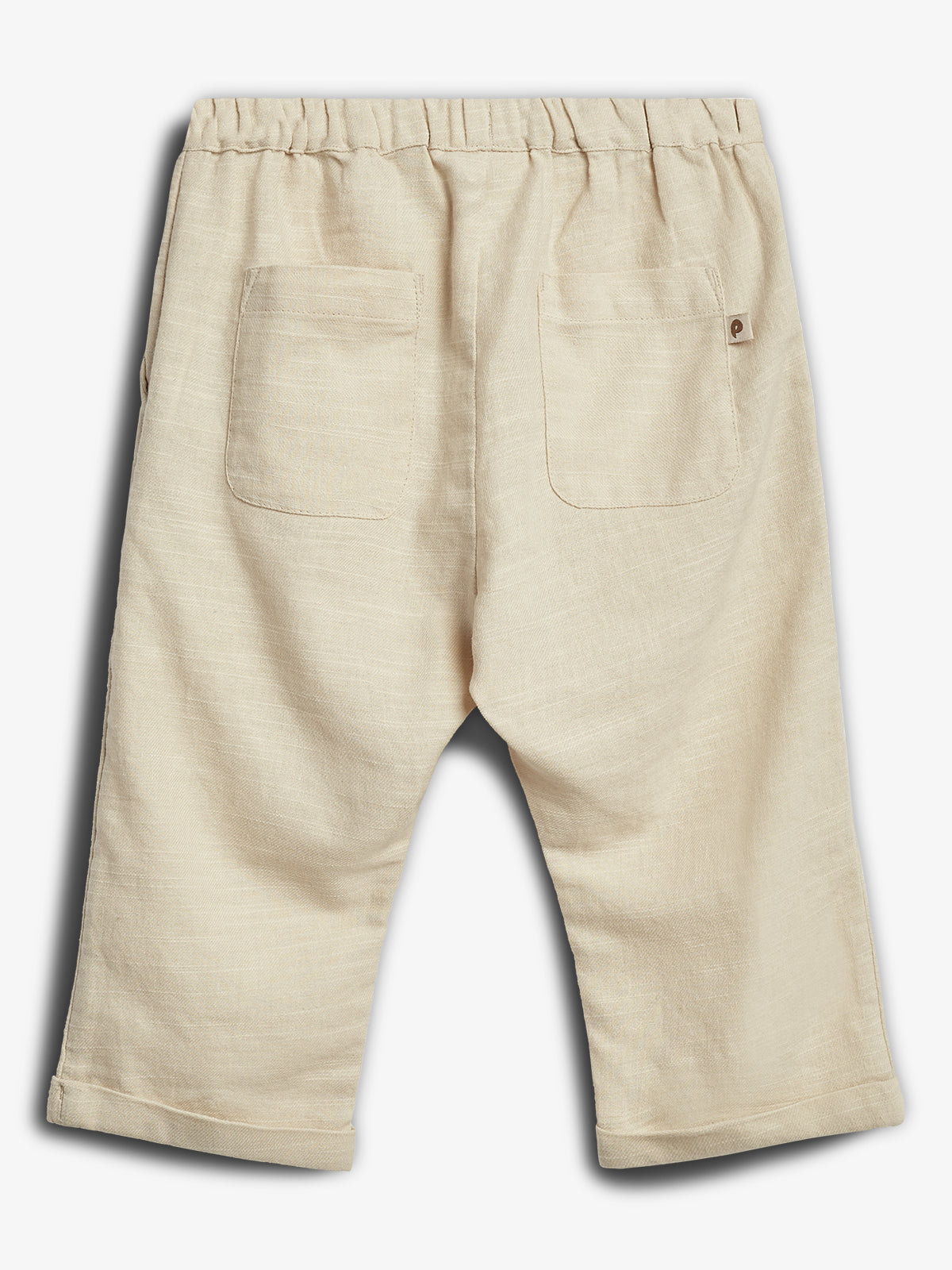 Een beige kinderbroek toont de achterkant met twee zakken; elastische tailleband. De broek ligt tegen een witte achtergrond.