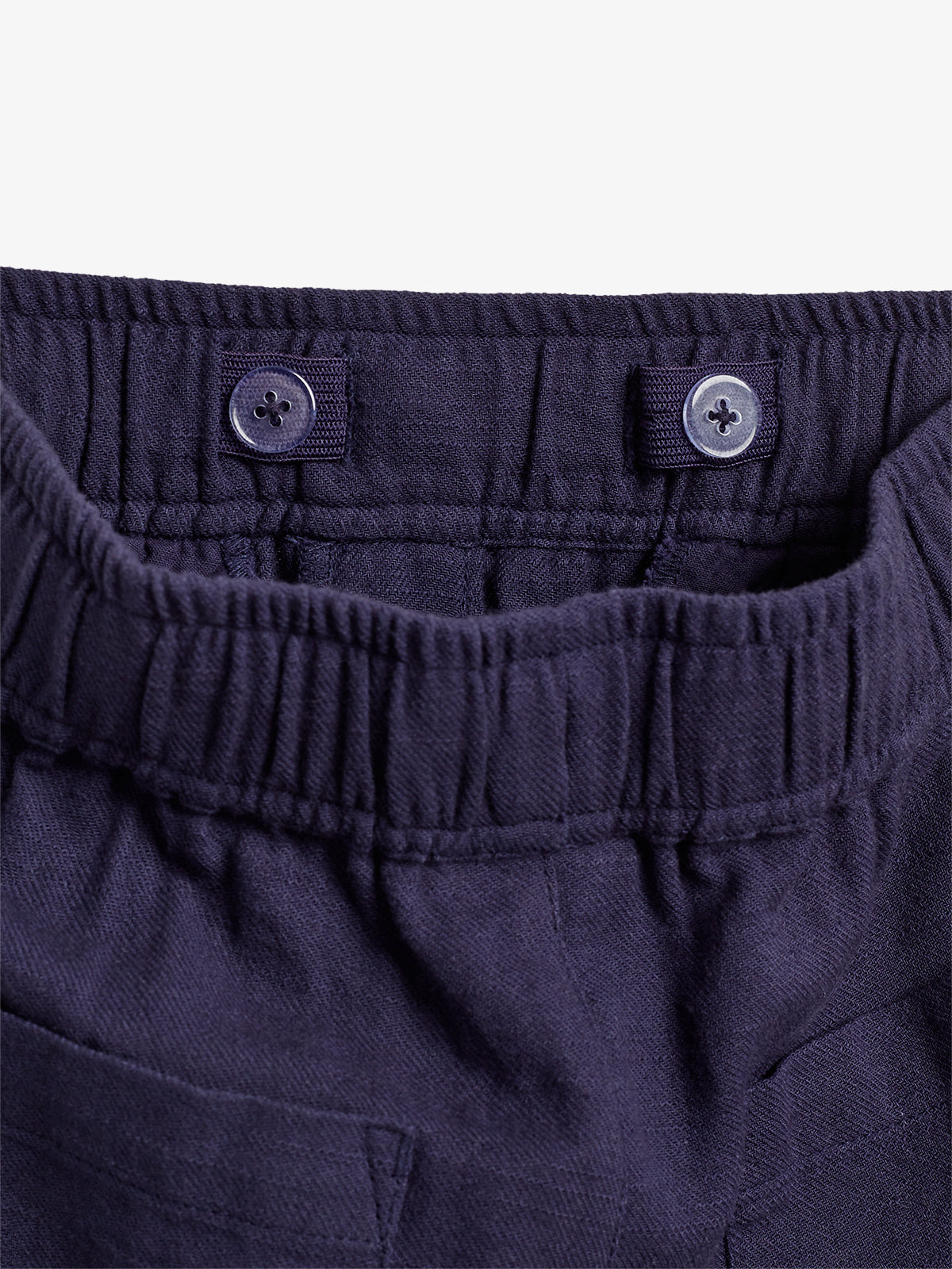 Elastic waistband pants with two buttons for adjustable sizing, shown in close-up to highlight the stitching and texture. The fabric appears dark blue in color.