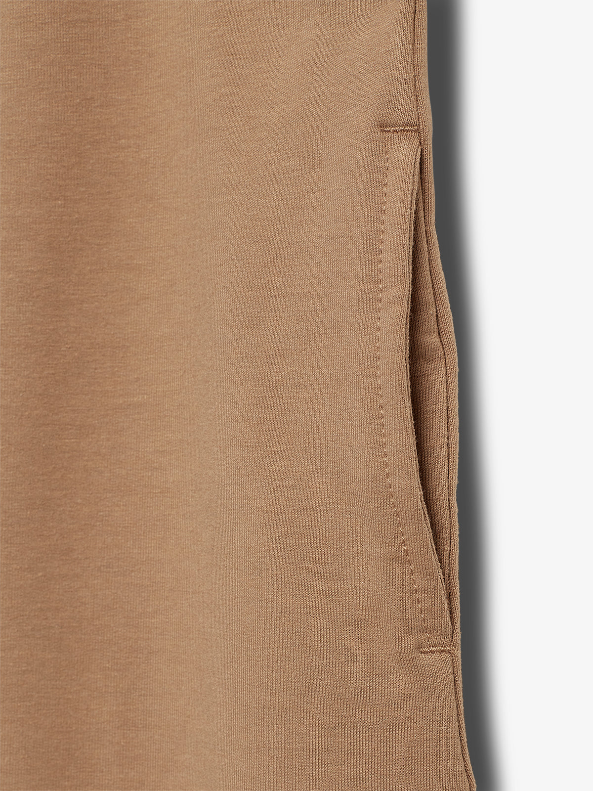 A close-up view of a brown fabric garment with a visible side pocket, showing detailed stitching and texture. The background is a plain white surface, enhancing the fabric's color.