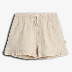 Cream-colored shorts with a drawstring waist and subtle floral pattern. The hem features ruffles, adding a decorative touch. The shorts are laid flat against a plain white background.