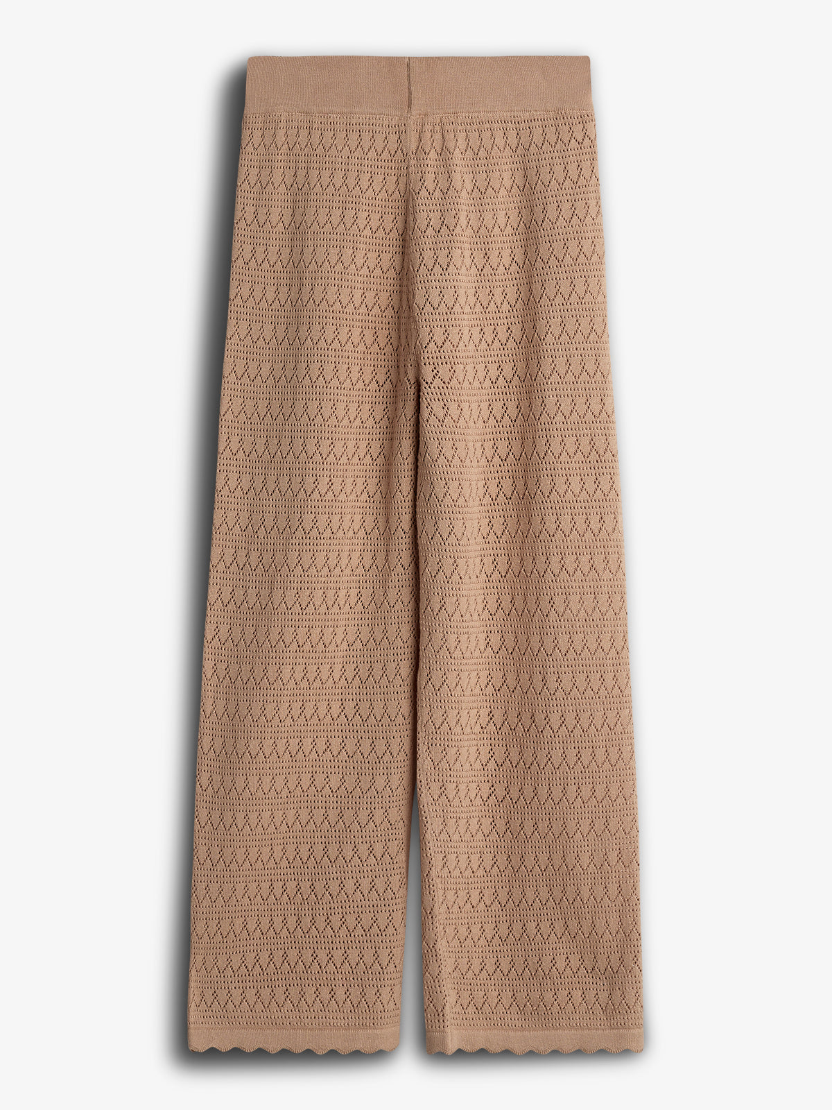 Beige knitted pants hang vertically, featuring a detailed zigzag pattern. The pants have a wide leg design and are set against a plain white background.