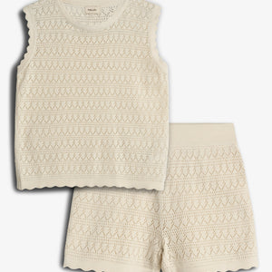 A cream-colored sleeveless knit top and shorts set lies against a plain background, showcasing a delicate diamond pattern and scalloped edges, exuding a soft and casual style.