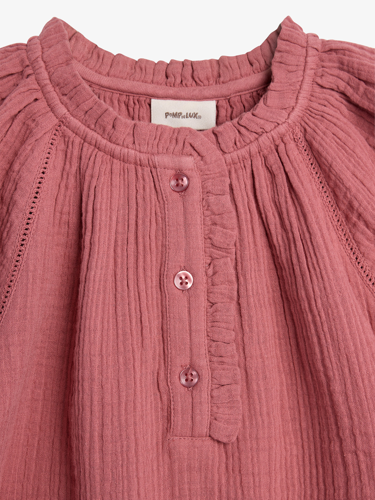 A pink textured fabric blouse features a button-down front with three buttons, a round neckline, and pleated detailing. Label reads "POMPELMO" near the collar.
