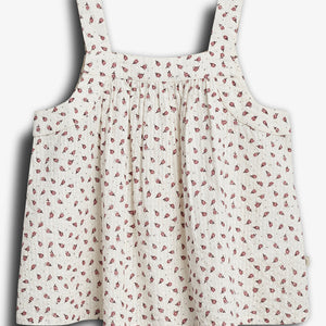 Sleeveless, floral-patterned dress with thick straps hangs against a plain backdrop. The fabric is light-colored with small, red floral designs scattered throughout.