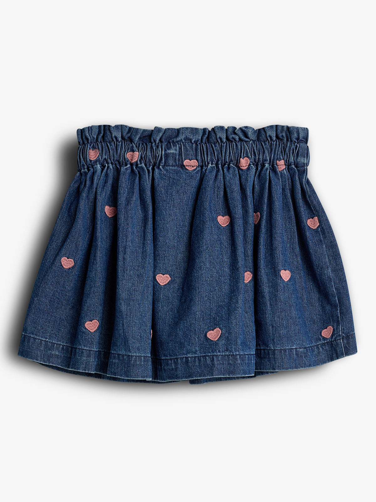 A blue, gathered skirt features pink heart embroidery scattered across its fabric, set against a plain, light background.