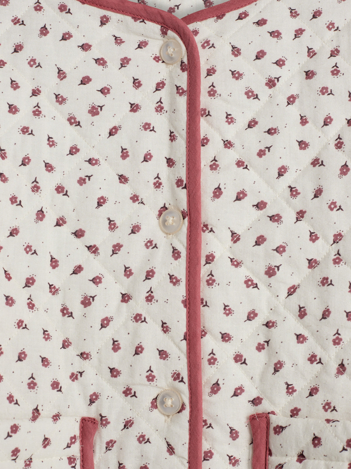 A quilted fabric with a small floral pattern in maroon on a light background; features buttons and maroon trim on the front, creating a delicate, cozy appearance.