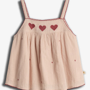 A light pink sleeveless top with red heart embroidery across the chest. It has thin straps and small scattered heart patterns, complementing a delicate, textured fabric.