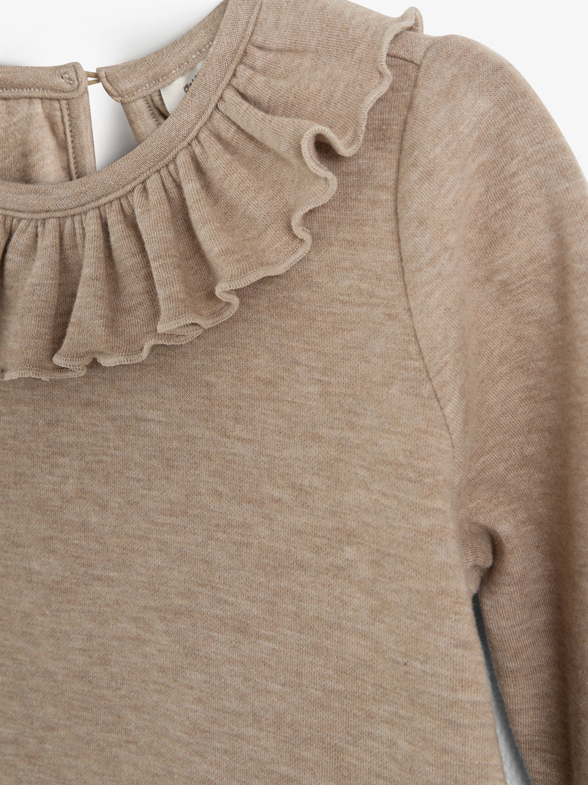 Beige trui met ruches rond de halslijn, zonder specifieke actie. Geplaatst tegen een effen witte achtergrond, toont een close-up van het materiaal en het detail van de hals.