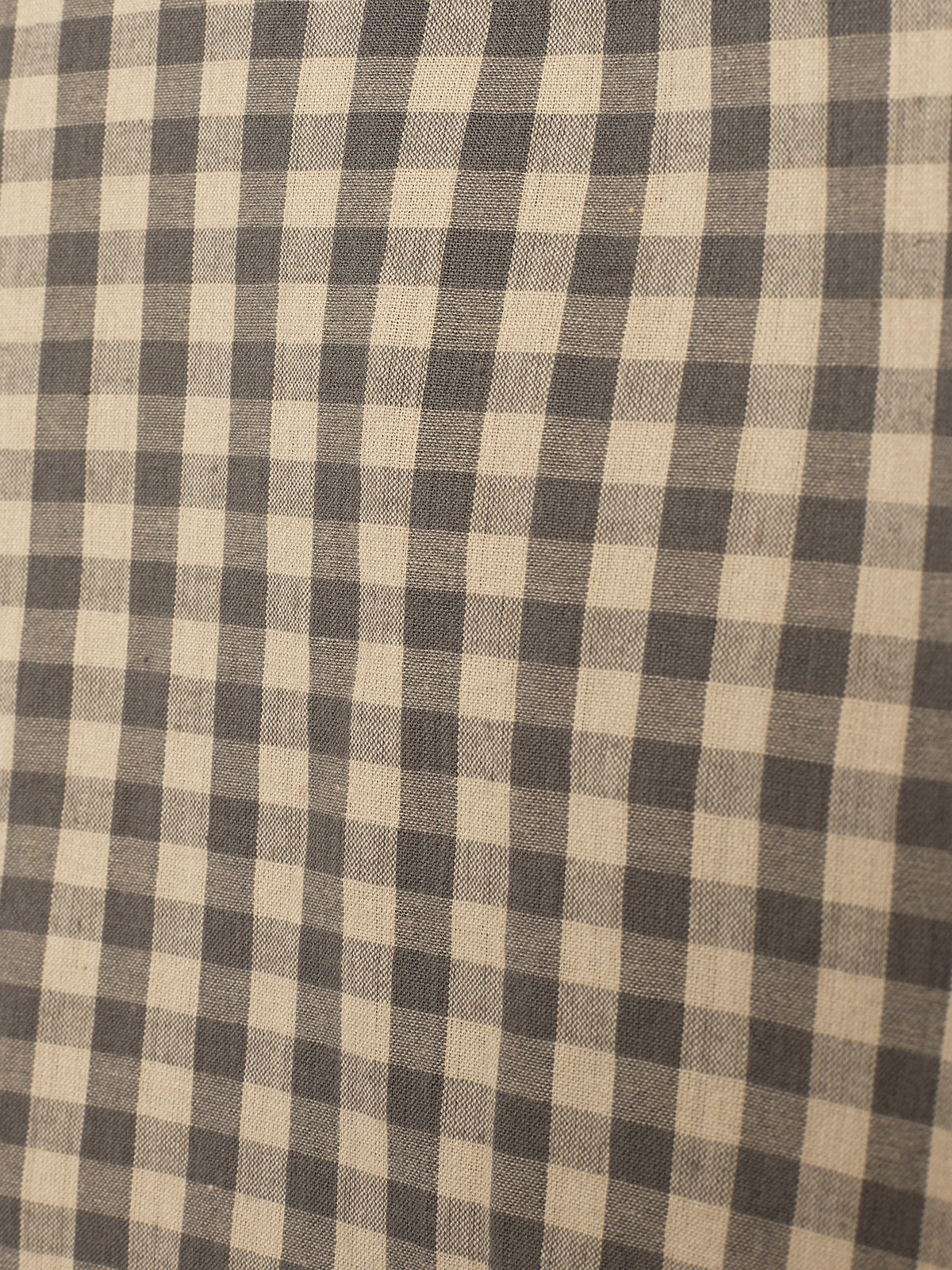 Stof met een geruit patroon in zwart en beige, met afwisselende vierkanten. Het weefsel creëert een rustieke uitstraling, waarschijnlijk geschikt voor kleding of decoratie. Geen tekst aanwezig.