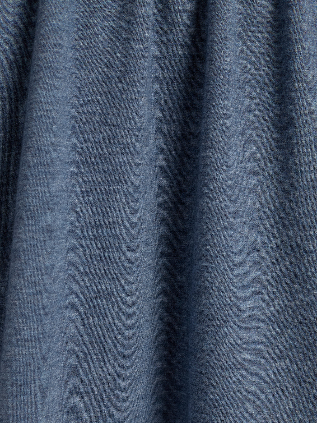 Stof hangt in zachte plooien. Donkerblauwe kleur met een subtiele, gemêleerde textuur. Geen zichtbare achtergrond, enkel de stof in close-up te zien.