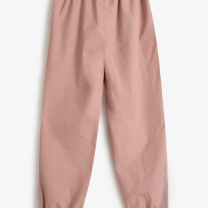 Roze regenbroek met elastische tailleband en enkels, liggend op een witte achtergrond. Er staat een tekst verticaal op het been: "FOREST SCHOOL".