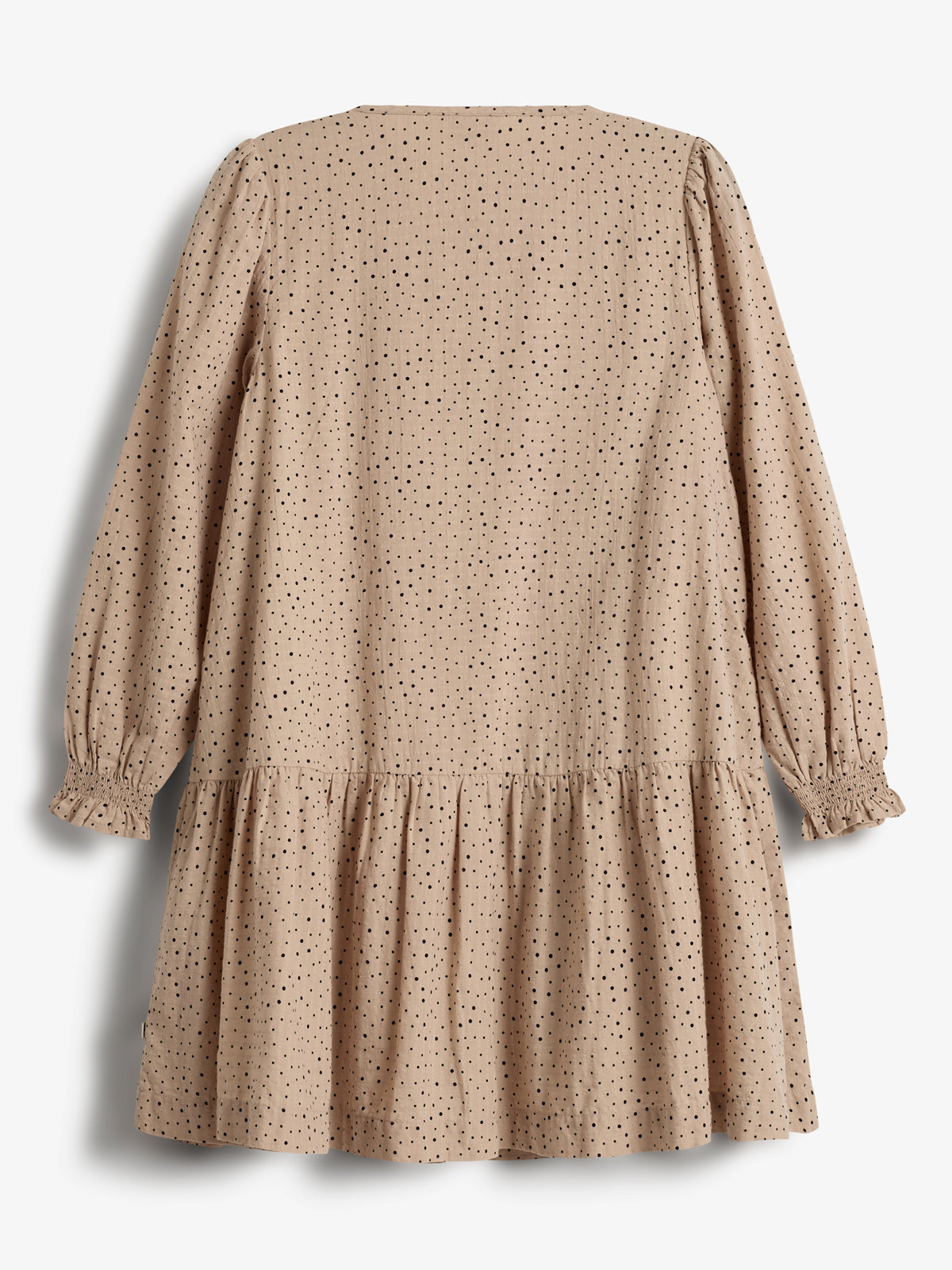 Een beige jurk met zwarte stippen; hangend met lange mouwen en een gerimpelde rok, in een lichte, eenvoudige omgeving zonder andere voorwerpen.