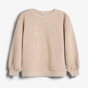Beige sweatshirt met de tekst "DANCING QUEEN" op de borst, hangt tegen een witte achtergrond. De trui heeft lange mouwen met elastische polsen.