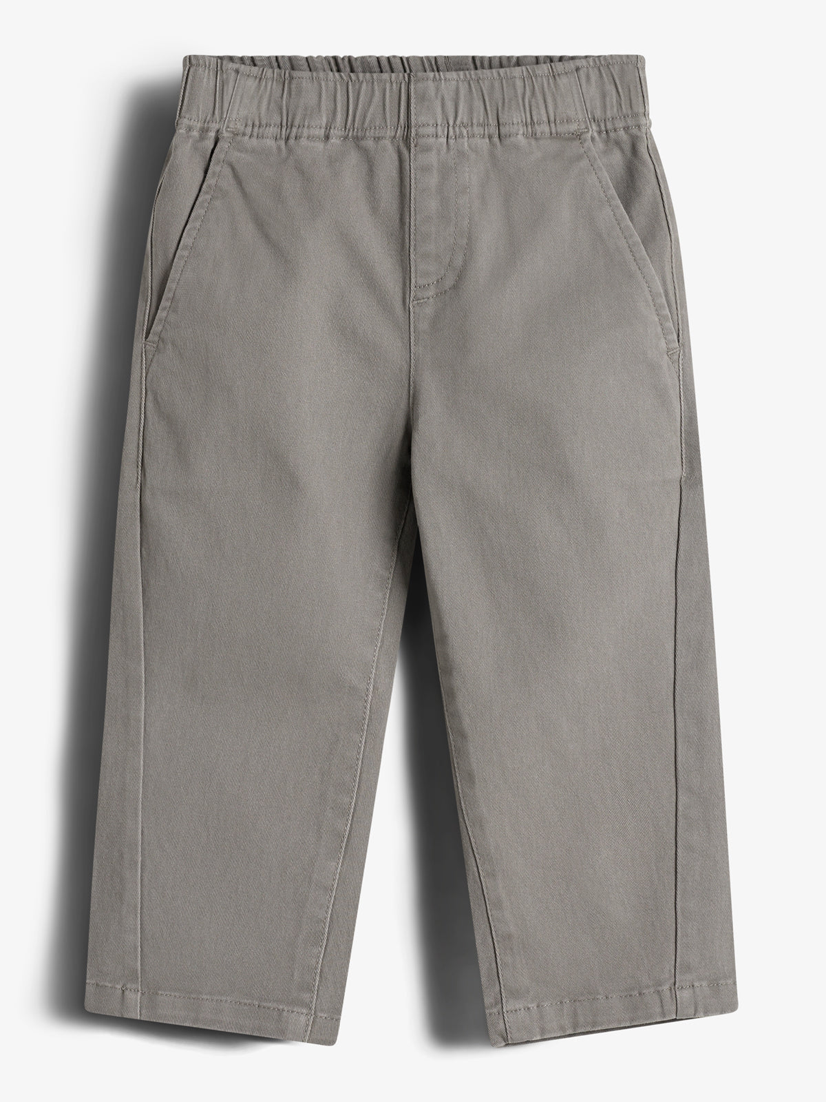 Een grijze kinderbroek met elastische tailleband en twee zijzakken, hangt tegen een effen witte achtergrond.