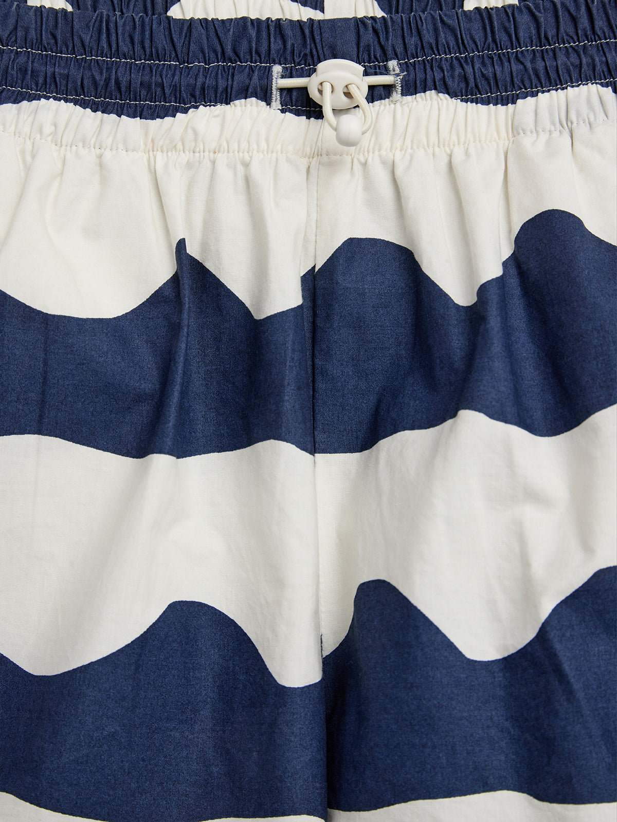 Korte broek met donkerblauwe en witte strepen, heeft een elastische tailleband met wit aansnoerkoord. Geplaatst tegen een neutrale achtergrond.