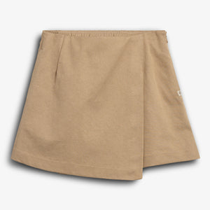 Een beige rok ligt plat, zonder versiering, met een subtiele plooi in het midden. De achtergrond is wit, en er is een klein label aan de zijkant.