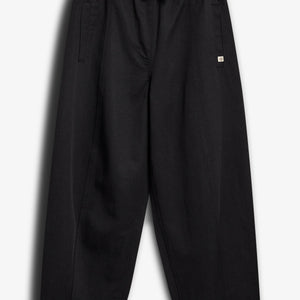 Een zwarte broek ligt plat. De broek heeft een elastische tailleband met een trekkoord en twee zakken. De achtergrond is effen wit.