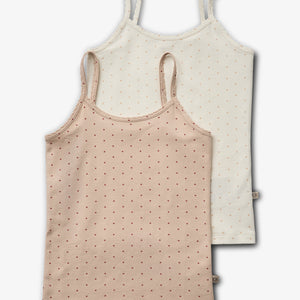 Twee hemdjes hangen overlappend. Het voorste hemdje is beige met kleine rode stippen, en het achterste is wit met vergelijkbare patronen. Beide hebben dunne schouderbandjes en zijn eenvoudig gestyled.
