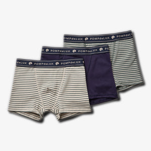 Drie paar boxershorts liggen naast elkaar. Twee hebben horizontale strepen, één is effen donkerblauw. De elastische tailleband heeft de tekst "POMPdeLUX". Geplaatst op een witte achtergrond.