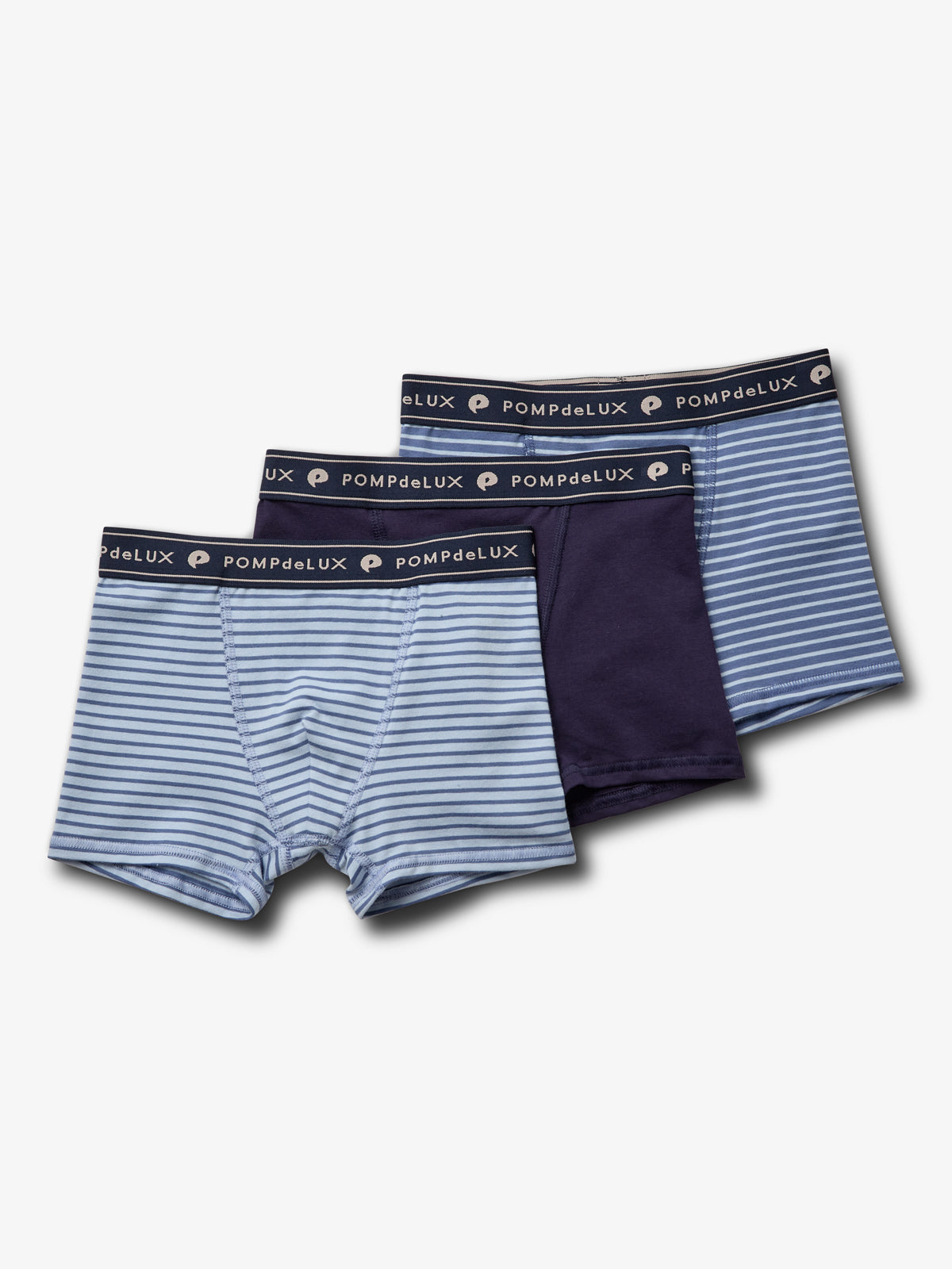 Drie jongensboxers liggen naast elkaar, één gestreept en twee effen. Elk heeft een elastische tailleband met de tekst "POMPdeLUX" erop, tegen een witte achtergrond.