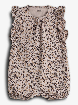 Een babyrompertje met ruches aan de schouders, bedrukt met een patroon van bruine en beige bloemen, hangt tegen een lichte achtergrond. Tekst bovenin: "PMP.CILK ORGANIC COTTON".