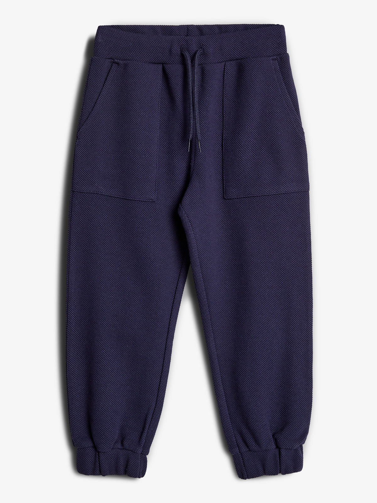 Een donkerblauwe joggingbroek met elastische tailleband en aantrekkoord. De broek heeft twee voorzakken en elastische boorden aan de enkels, weergegeven tegen een witte achtergrond.