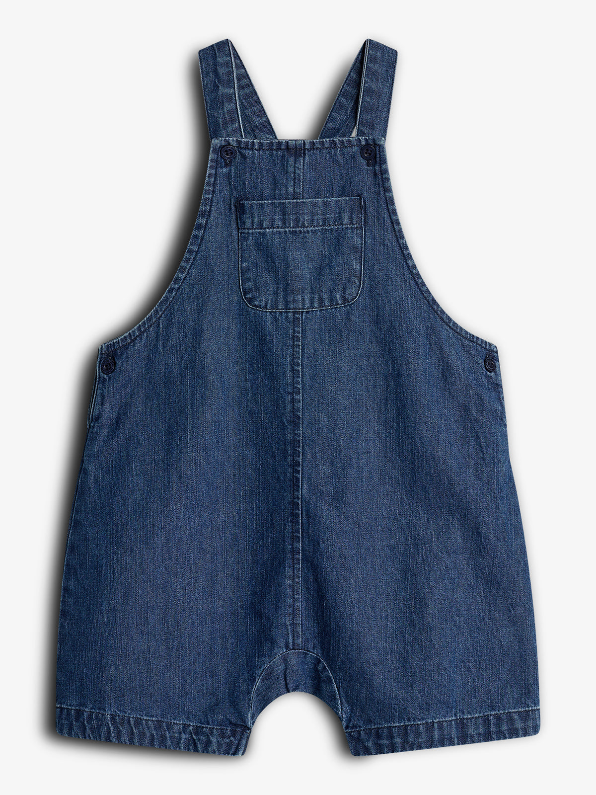 Denim kinder tuinbroek met bretels, liggend tegen een effen witte achtergrond. De broek heeft een borstzak aan de voorkant en knopen bij de schouderbanden en zijkanten.