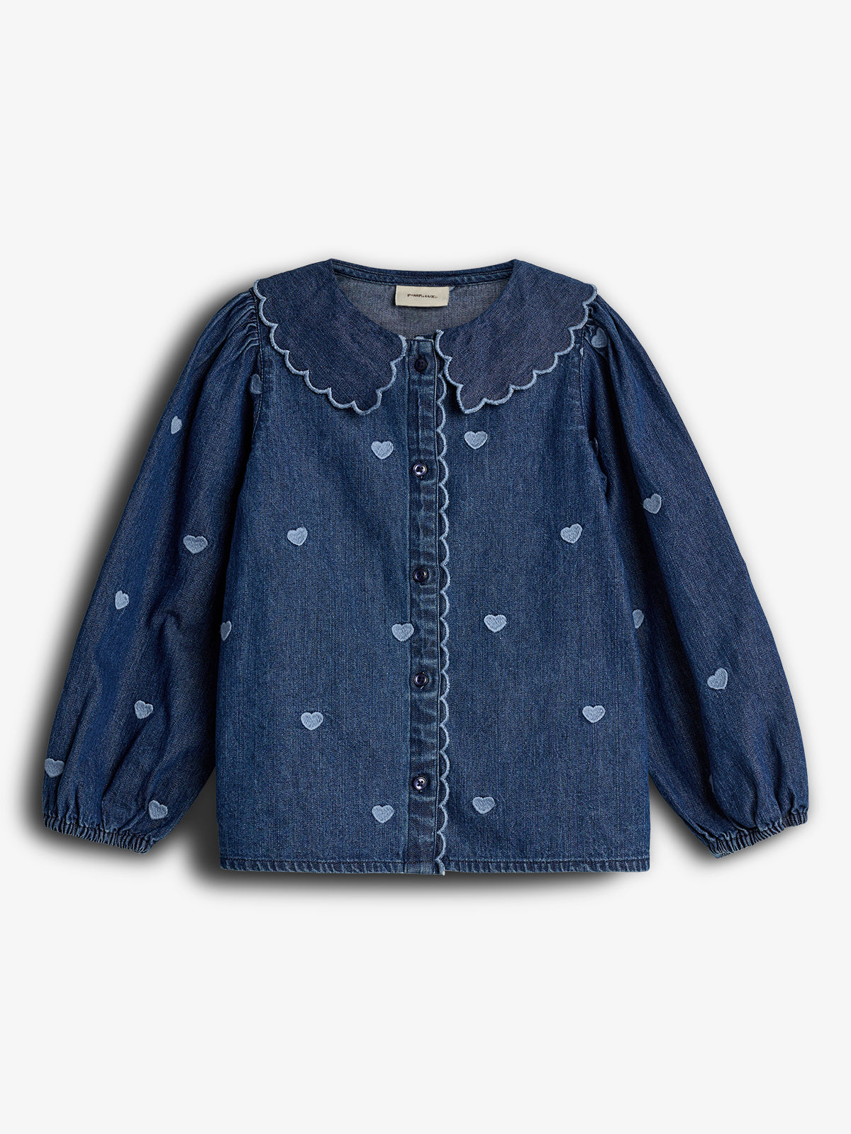 Blauw, denim meisjesblouse met lange mouwen, versierd met kleine hartjes en een geschulpte kraag. De blouse heeft knopen in het midden en een witte achtergrond.