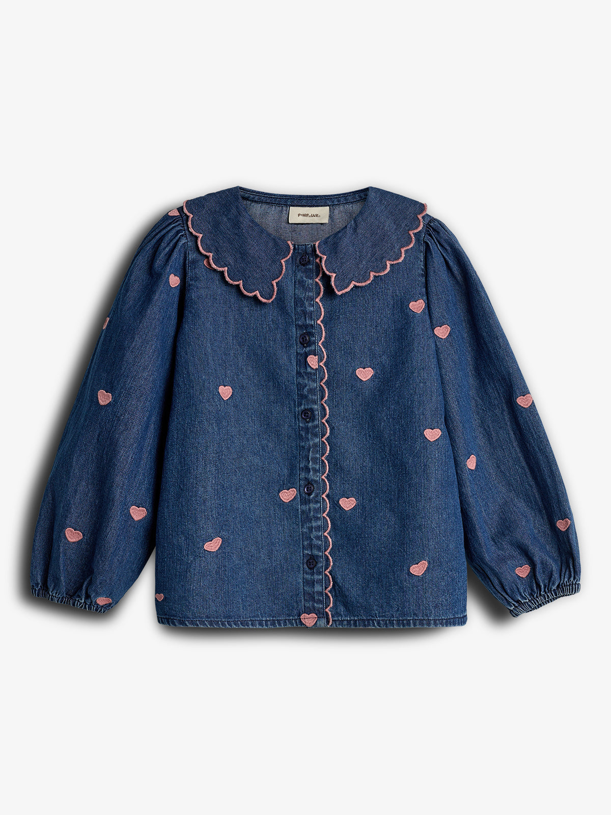 Denimblouse met roze hartjespatroon en geschulpte kraag, knopenrij in het midden. De blouse heeft lange pofmouwen en bevindt zich tegen een effen, lichte achtergrond. Label zonder tekst zichtbaar aan de binnenkant van de kraag.
