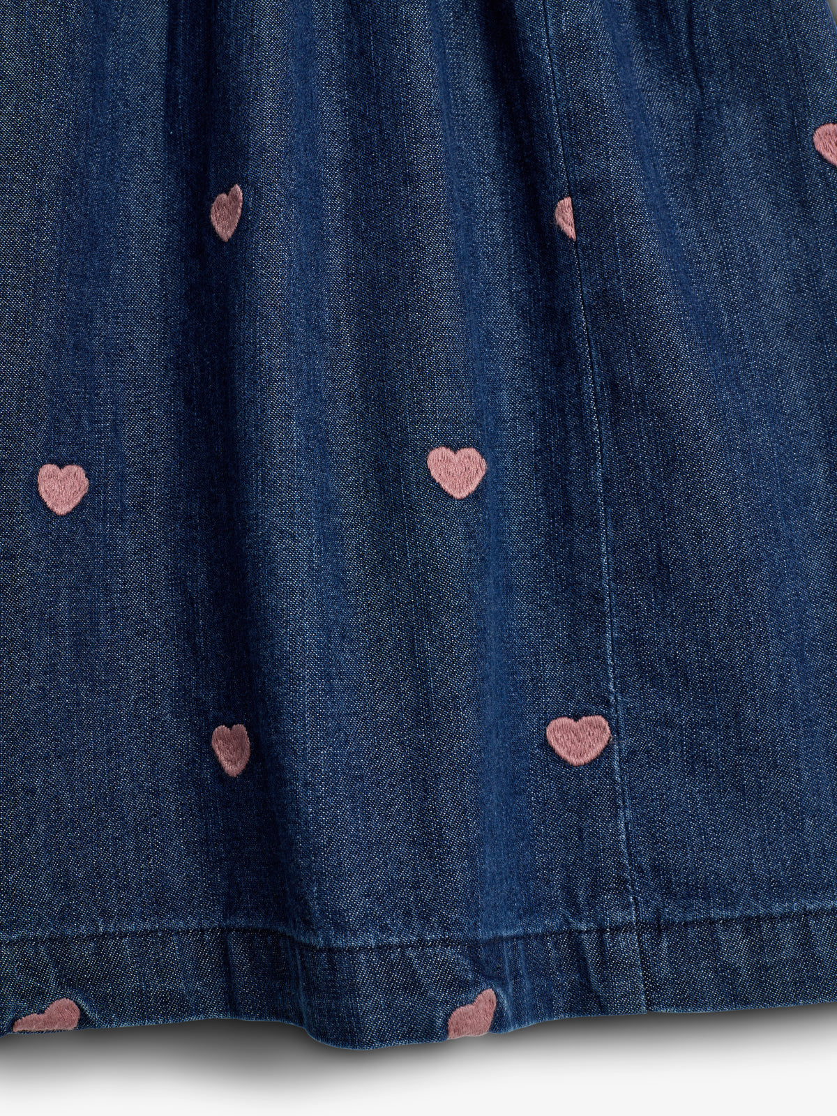 Donkerblauwe denim stof, versierd met kleine roze hartvormige patronen verspreid over het oppervlak, in een eenvoudige en elegante stijl.
