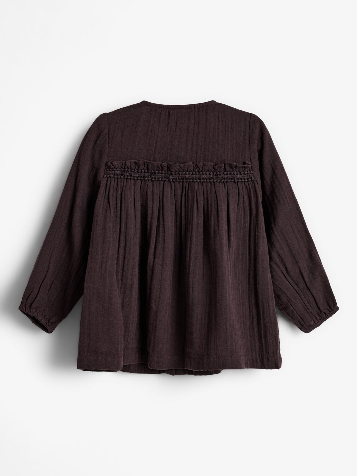 Een donkerbruine, lange mouwen blouse met een geplooid ontwerp en elastische uiteinden, hangt tegen een witte achtergrond. De blouse heeft decoratieve ruches en een borduurwerk net onder de schouders.