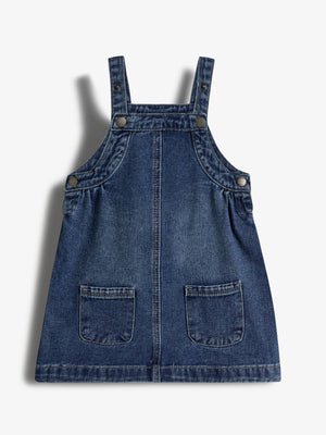Denim pinafore-jurk, onbeweeglijk op afbeelding, met twee zakken en schouderbandjes met knopen. Geen tekst zichtbaar. De context is een effen witte achtergrond.