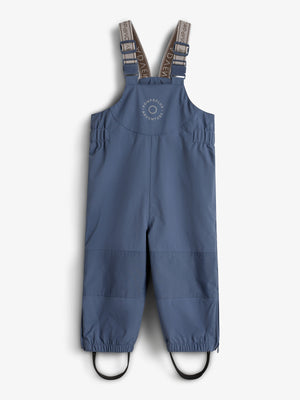 Een blauwe kinderregenbroek met verstelbare schouderbanden en elastische enkels, ontworpen voor avonturen. Op de borst staat de tekst “ROMPDELUX ADVENTURE”. Het hangt tegen een neutrale achtergrond.
