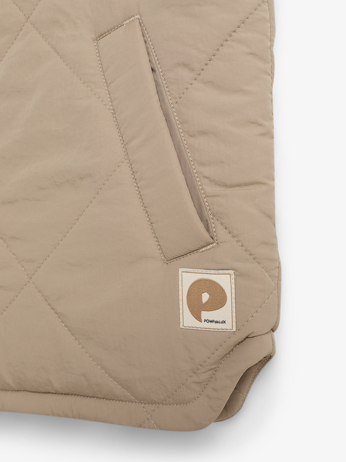 A beige quilted fabric with a diagonal pocket and a stitched logo patch reading "POMPEIIUX" is shown, featuring geometric stitching patterns against a plain background.