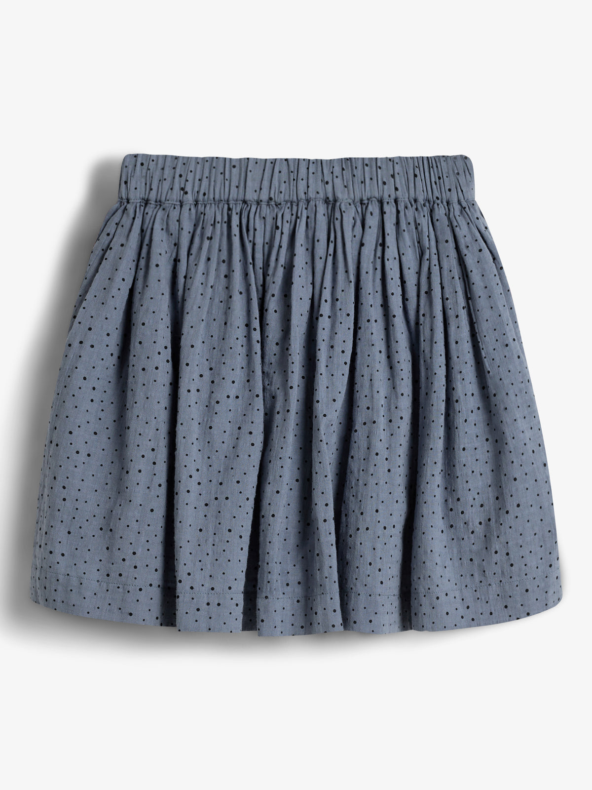 A blue, knee-length skirt with small black polka dots hangs loose, featuring an elastic waistband. It is displayed against a plain white background.
