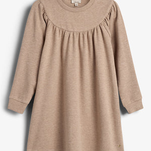 Beige jurk met lange mouwen, hangend aan een witte achtergrond. Het heeft een ronde halslijn en plooien op de borst. Labeltekst: "mini, love".