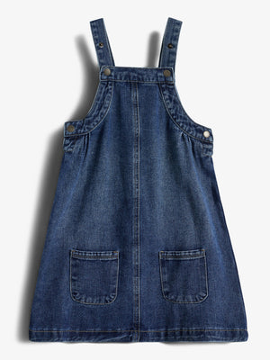 Blauwe denim jurk met schouderbanden en zakken aan de voorkant, liggend op een witte achtergrond. Bevestigingsknopen zijn zichtbaar op de bandjes en zijkanten.
