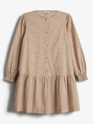 Beige jurk met lange mouwen, bedekt met zwarte stippen en knopen aan de voorkant. De jurk heeft een geplooide zoom en is gefotografeerd tegen een witte achtergrond.