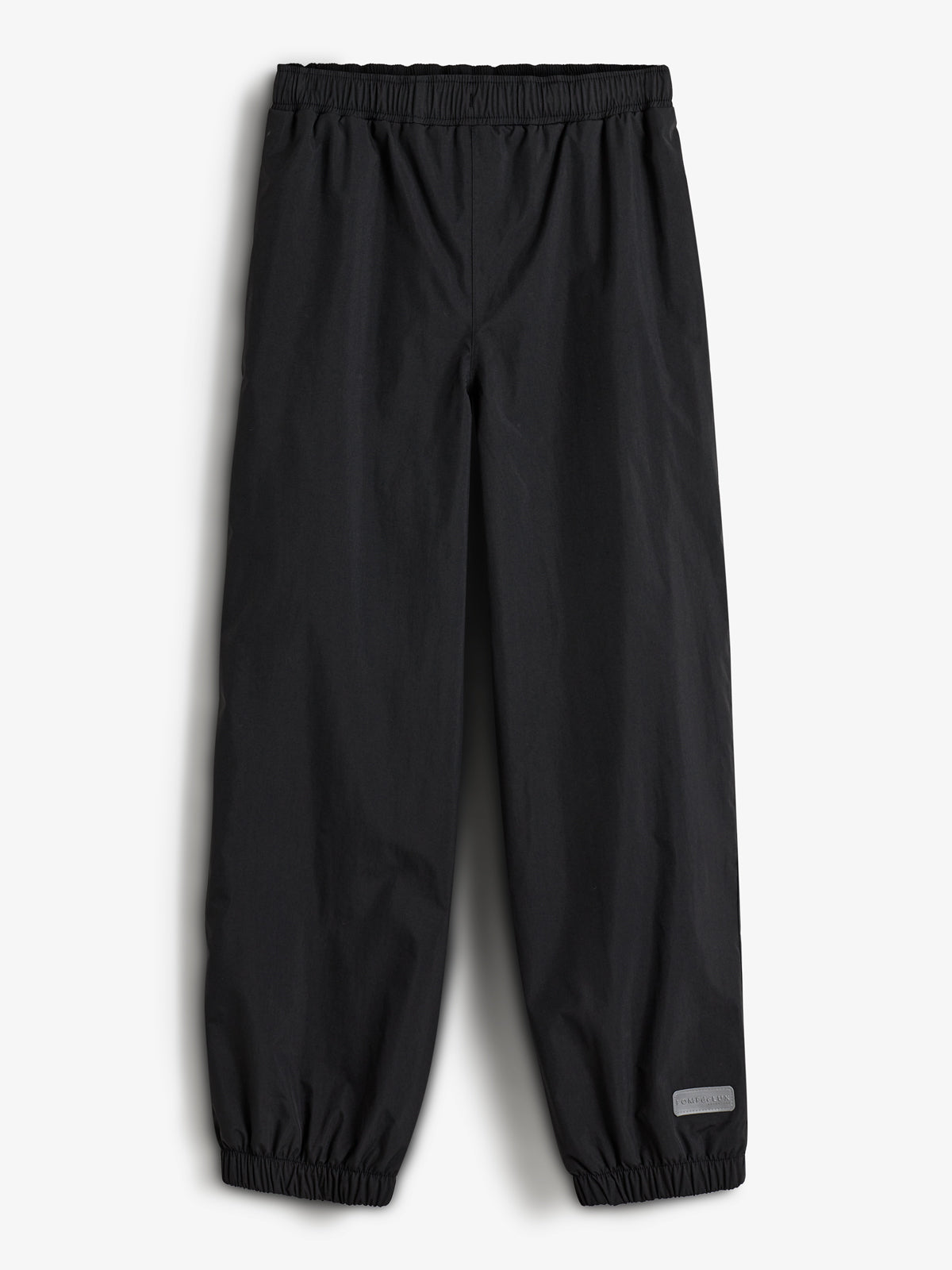 Een zwarte broek ligt plat met elastische tailleband en enkelboorden. In de rechteronderhoek bevindt zich een grijs label met de tekst "Lindex". De achtergrond is wit.
