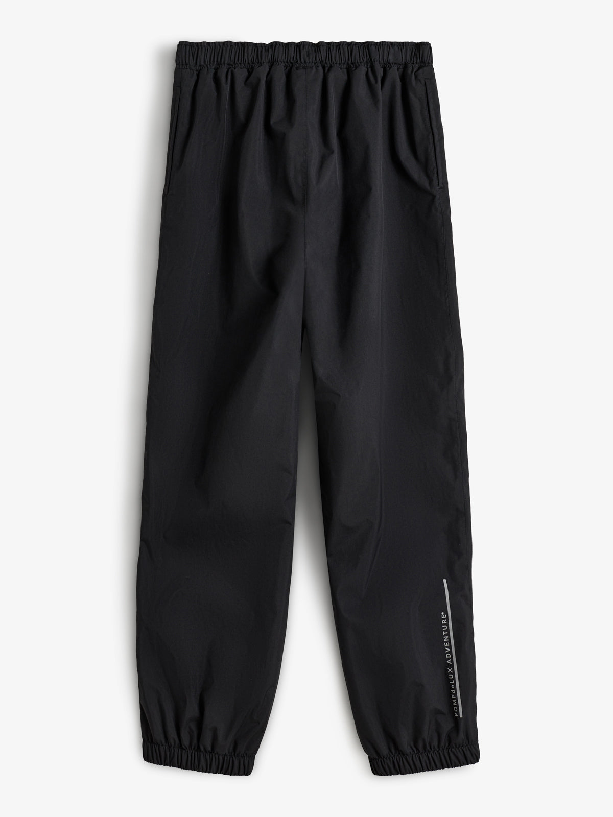 Zwarte broek met elastische taille en enkels, horizontaal neergelegd tegen een witte achtergrond. In witte tekst staat: "Adventure Communauté Aventure."